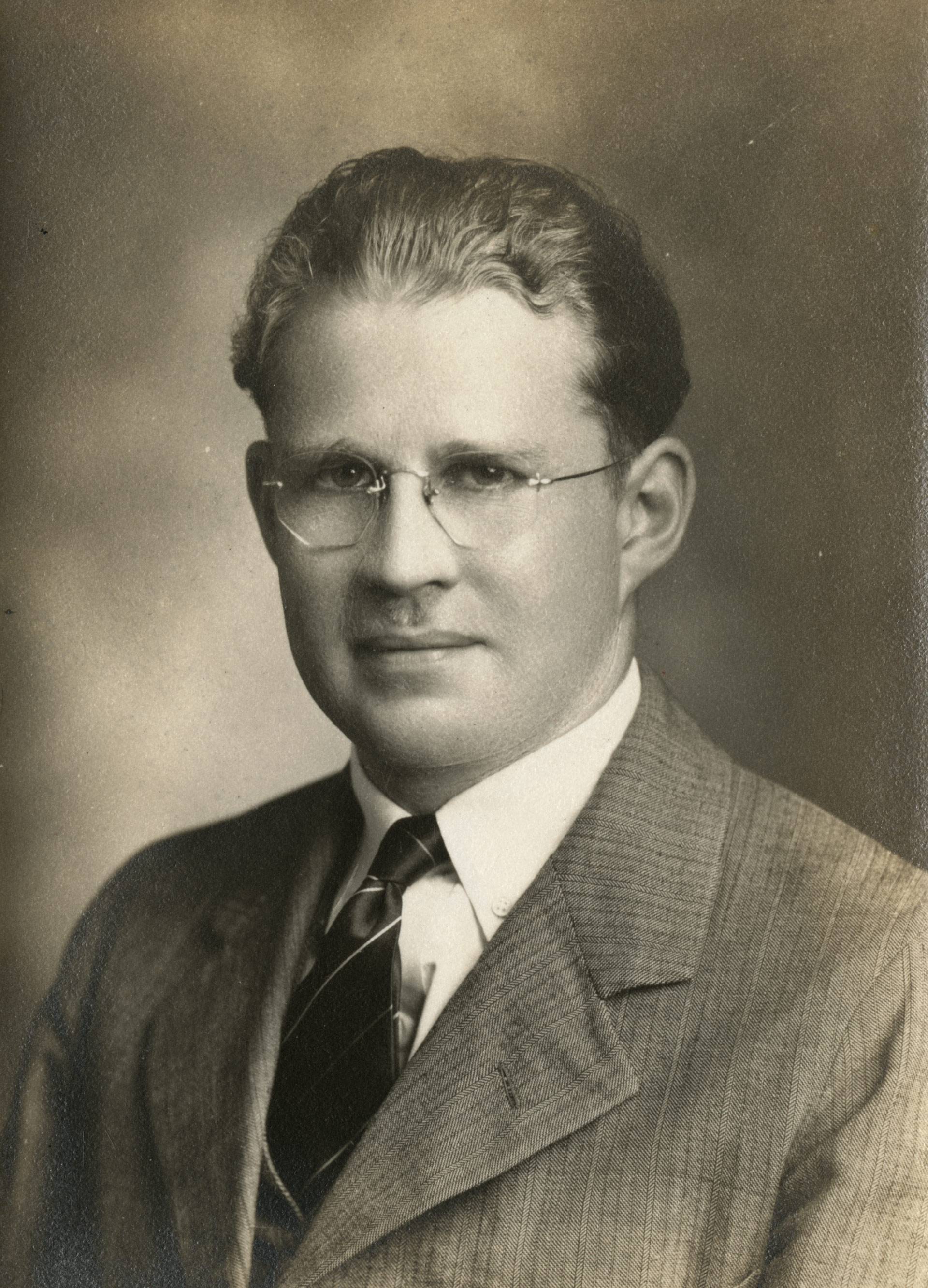 A young Wilfrid Sellars gazes forward. The picture is an old black and white and he is in his 20's or 30's wearing a tweed jacket.